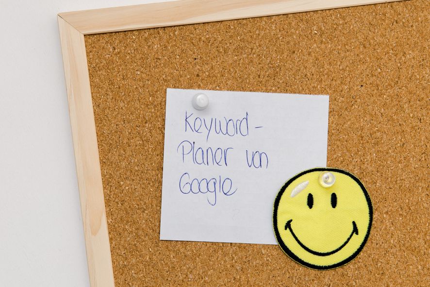 Begleitbild zu Abschnitt Website frisch und sichtbar machen: Korkenpinnwand mit Notiz Keyword-Planner und Smiley-Bild